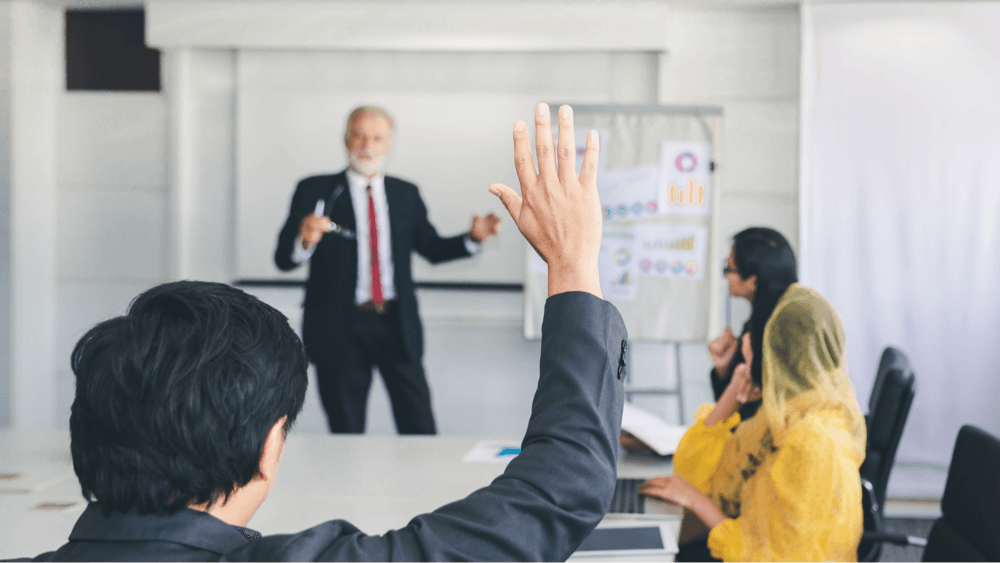 person raising hand in meeting